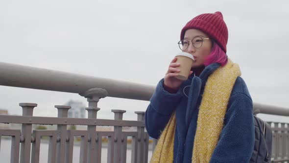 Asian Female Tourist Drinking Coffee on City Riverside and Looking Around