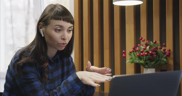 Portrait of a Young Girl in Headphones Talking in Front of a Laptop Screen