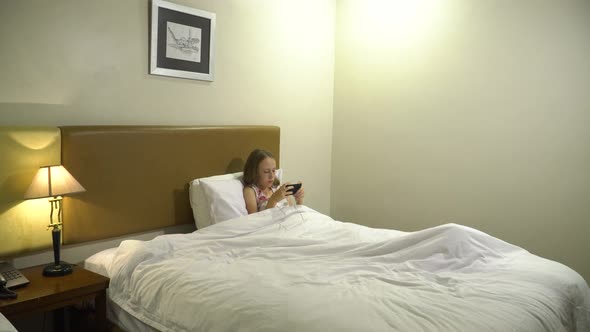 Girl in Bed with a Smartphone in Her Hands