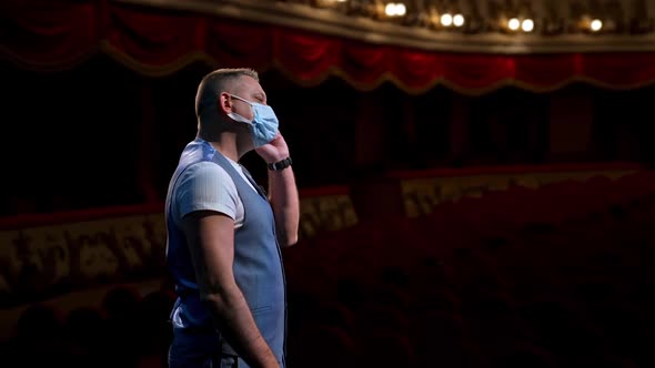 Actor puts facial mask off and annonces beginning of thater season beginning. Happy man on stage.