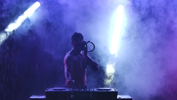 Silhouette of a Sports Half-naked Male Disc Jockey Working on the Controller. A Professional DJ