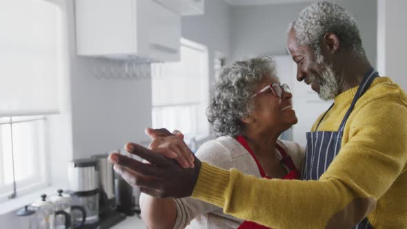 A senior african american couple spending time together at home dancing in the kitchen social distan