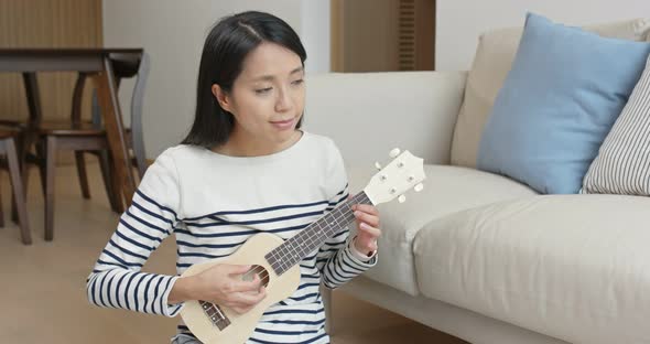 Woman play ukulele at home