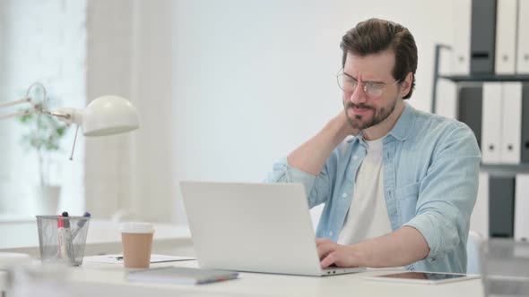 Young Man with Neck Pain Working on Laptop