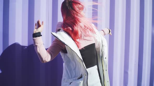Happy Young Funky Woman with Pink Hair Dancing on Coloured Background