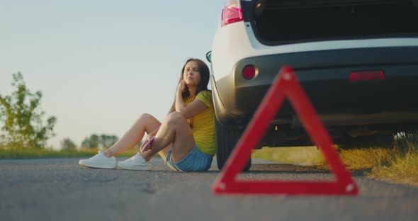 Upset Girl Sits By a Broken White Car with No Phone Connection