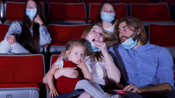 Family in masks in movie theater