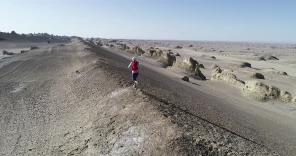 Aerial footage of woman trail runner cross country running  on sand desert dunes