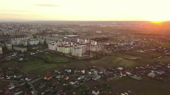 Aerial view of high residential apartment buildings and private houses in suburbun area at sunset