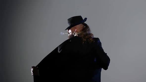 Elegant Man in a Black Hat Is Dancing an Erotic Dance. Spotlight on a Black Background. Close Up