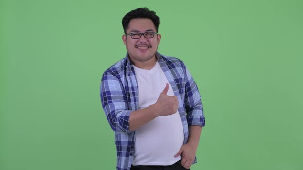 Happy Young Overweight Asian Hipster Man Giving Thumbs Up