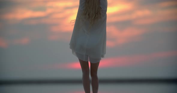 Beautiful Sunset Sky in the Background of a Young Woman on the Pier