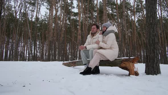 Man and Woman Sit on a Log and Relax