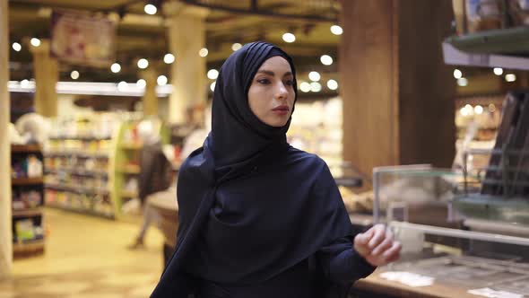 Woman in Hijab Takes Pile of Products From the Shelf in the Supermarket