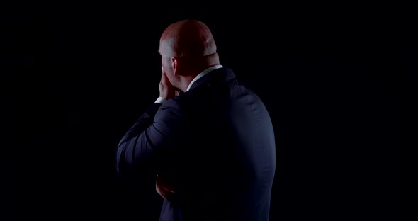 A Close-up Portrait of a Bald, Middle-aged Man in a Business Suit, Jacket, and Shirt and Tie. It