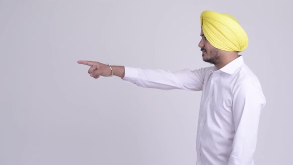 Profile View of Happy Bearded Indian Sikh Businessman Pointing Finger
