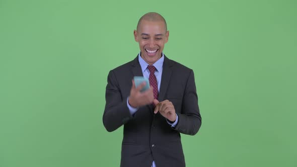 Happy Bald Multi Ethnic Businessman Using Phone and Getting Good News