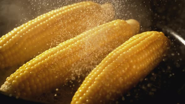 Sprinkling salt on corns in fry pan. Slow Motion.