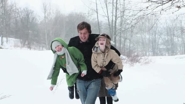 Father carrying son and daughter in snow