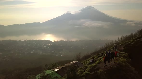 Four Hiker Friends Standing On Top of Mount Batur Volcano and Watching Beautiful Sunrise. Aerial