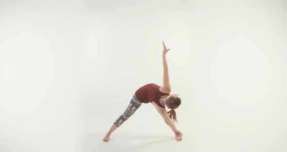 Young attractive woman performing Yoga routine on a white studio background