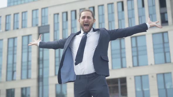 Successful Handsome Businessman Stretching Hands with Joy and Smiling at Camera. Portrait of Young