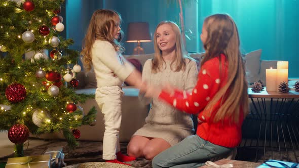 Mother Playing with Two Daughters Near Christmas Tree