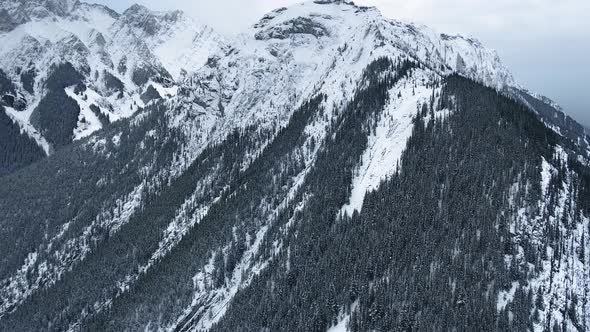 Bird's eye view of mountain peaks and winter forest on the slopes in Kananaskis, Alberta, Canada
