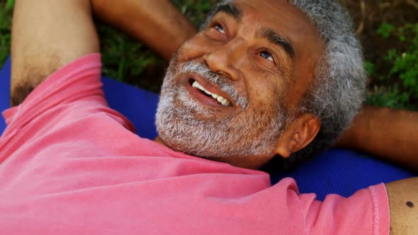 Senior man lying on exercise mat in garden 4k