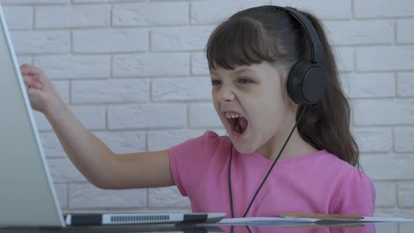 A child on a laptop listens to music.
