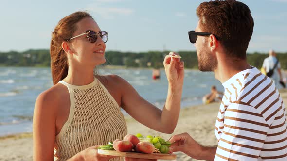 Happy Couple with Food Having Picnic on Beach