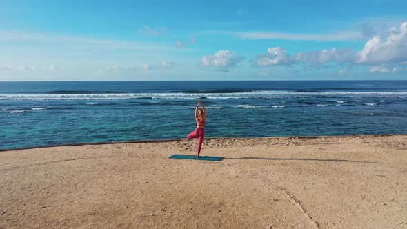 Drone Footage Woman Does Yoga Exercises and Stretches at Beach with Ocean View 