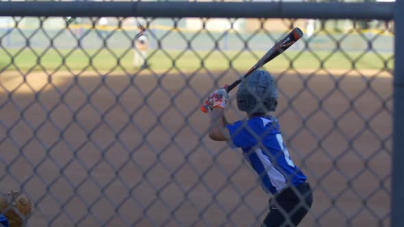 A batter makes a strike while playing in a boys little league baseball game.