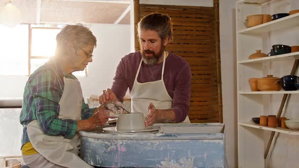 Male potter assisting female potter