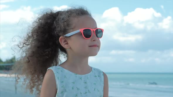 Close-up Portrait of a Beautiful Little Girl in Pink Glasses, Cute Smiling, Looking at the Sea