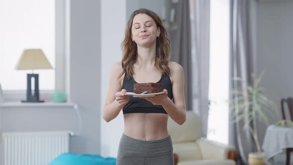 Medium Shot of Slim Beautiful Woman Eating Delicious Sweet Dessert Standing at Home Indoors