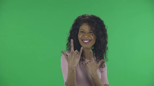 Portrait of Beautiful African American Young Woman Is Looking at Camera and Making a Rock Gesture