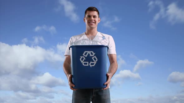 Man against sky holding recycling bin with plastic bottles