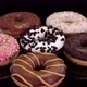 Different donuts with icing and colorful sprinkle rotating on a black background.  - VideoHive Item for Sale
