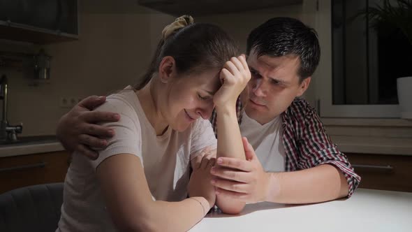 Upset and Stressed Woman Crying and Hugging Her Husband on Kitchen at Night