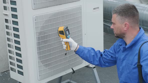 Technician uses a thermal imaging infrared thermometer to check the condensing