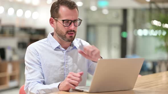 Sick Businessman with Laptop Coughing in Office