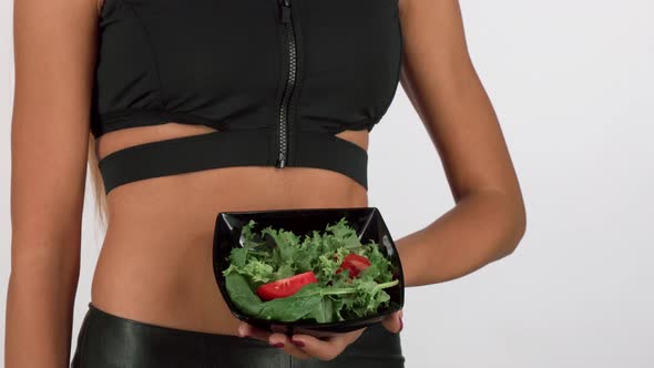 Athletic Woman in Sportswear Holding a Bowl of Fresh Salad