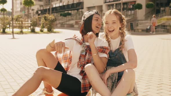 Two young smiling beautiful girls with colorful penny skateboards