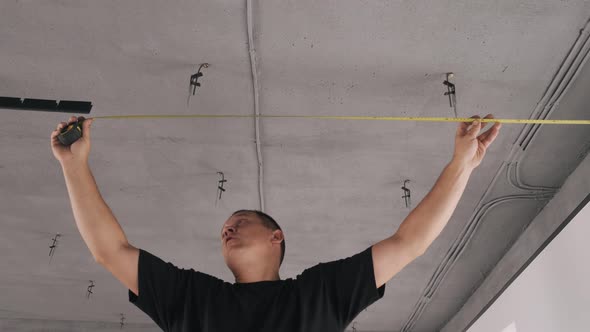 Professional Worker Measuring Ceiling with a Tape