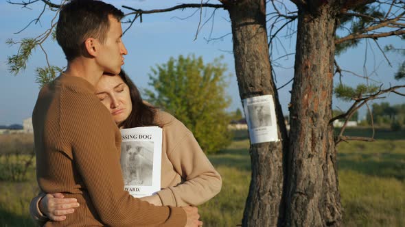 Man Hugs Girlfriend Near Poster of Missing Dog in Park