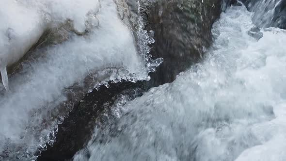 Flowing water in river close up. Winter Icy river with water streams, stones and ice