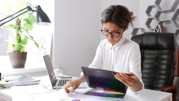 Beautiful Female Designer Writing in Folder Sitting in Office Slow Motion