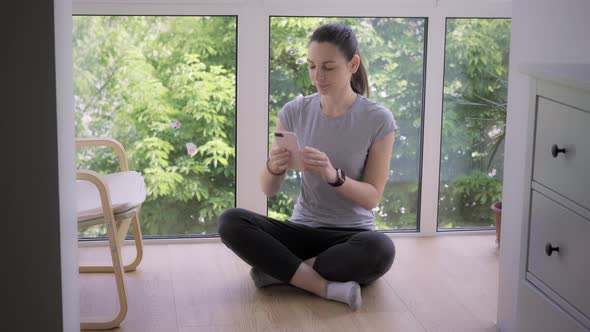 Young Woman with Phone Meditating with Online Trainer or Influencer. App for Meditation. Covid-19