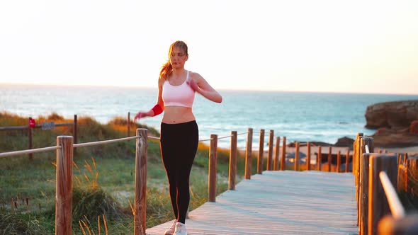 Flexible Caucasian Girl Stretches Legs After an Intensive Running Workout